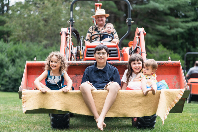 Family sitting in tractor at home in weathersfield, vt