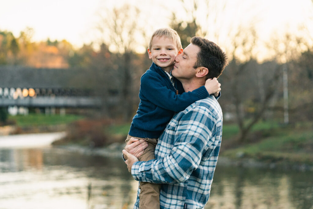 woodstock vermont family photo session: father blowing raspberries on childs neck