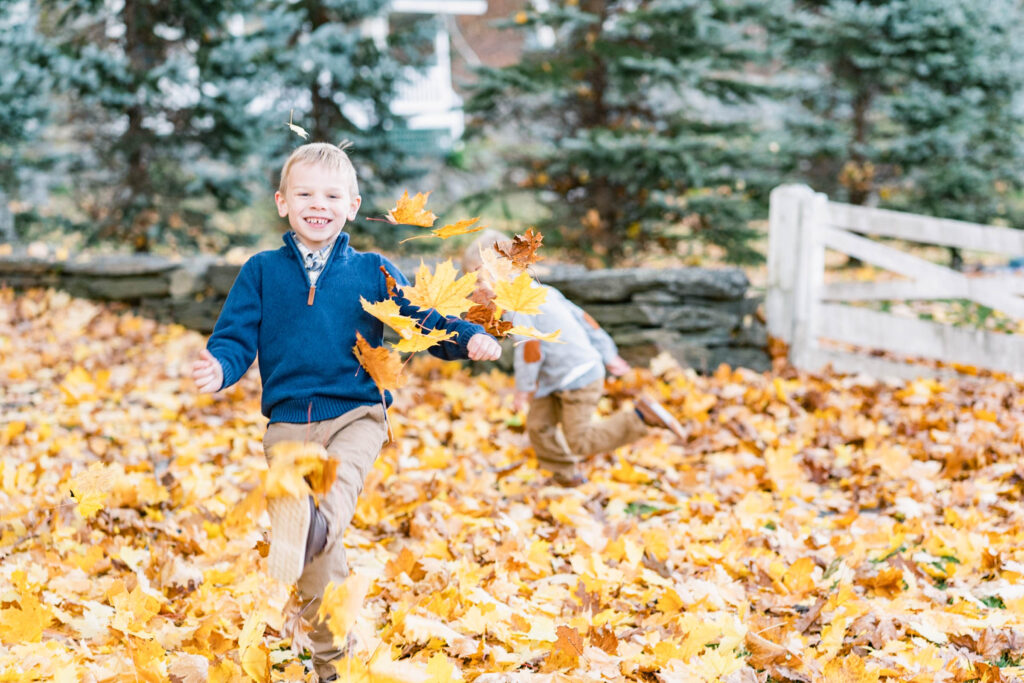 woodstock vermont family photo session: boys playing in autumn leaves in woodstock