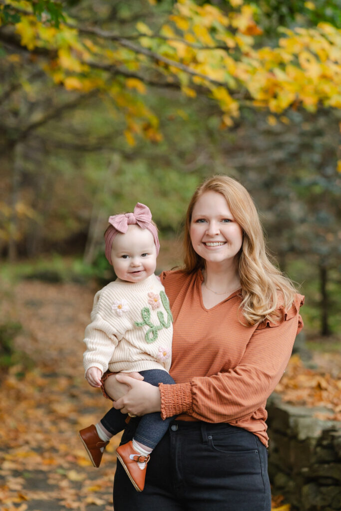 mother sitting on stone wall with baby woodstock vermont fall family photo session