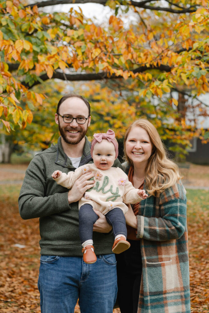 parents holding baby outward and smiling at camera during woodstock vermont fall family photo session