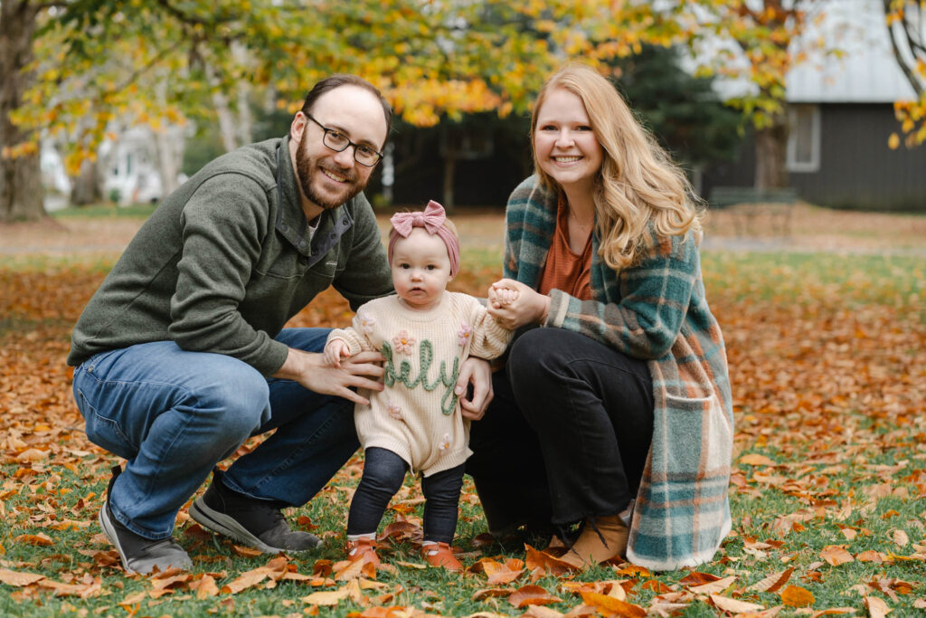 parents kneeling with baby during woodstock vermont fall family photo session