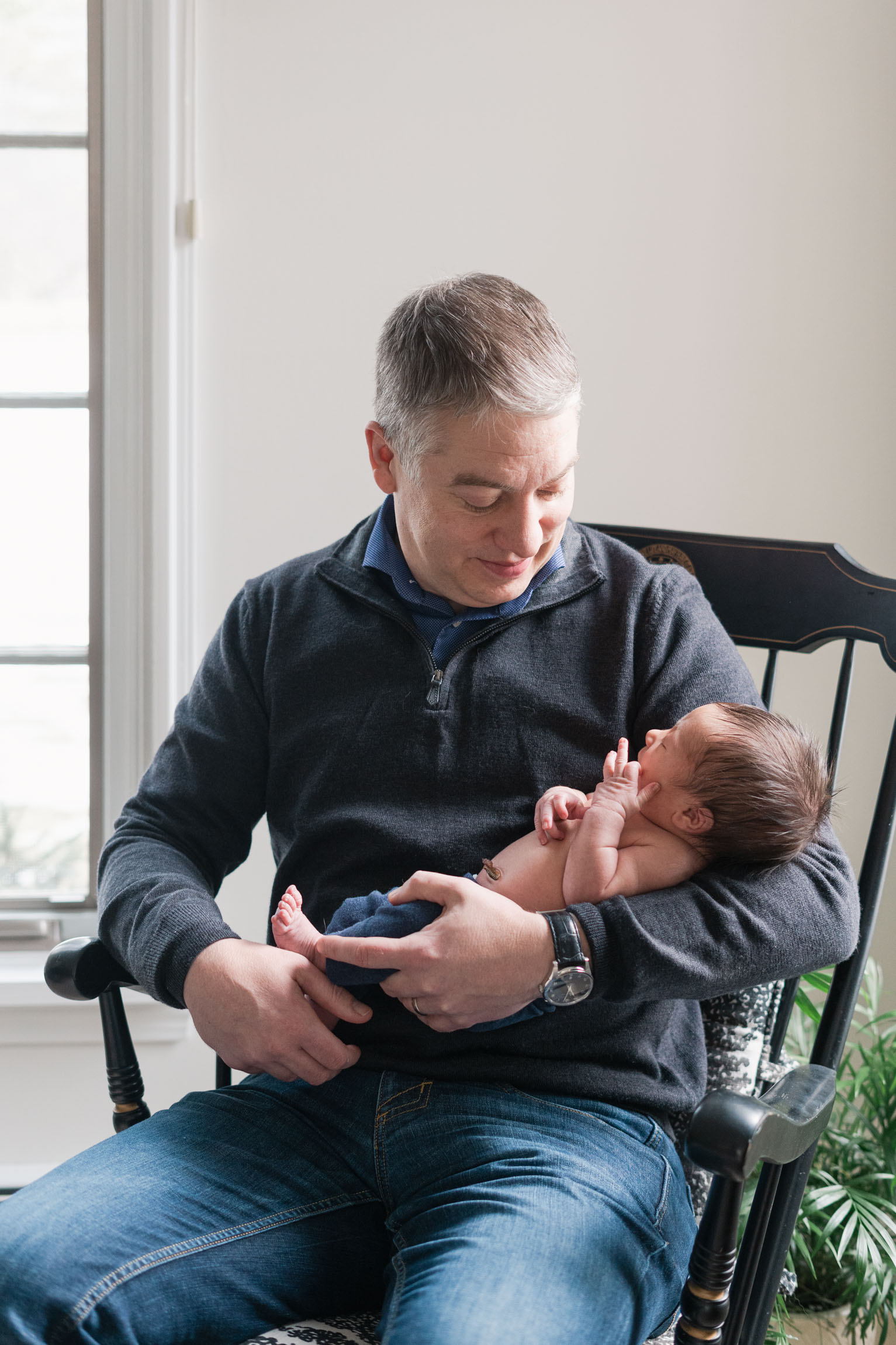 father sitting in rocking chair holding son