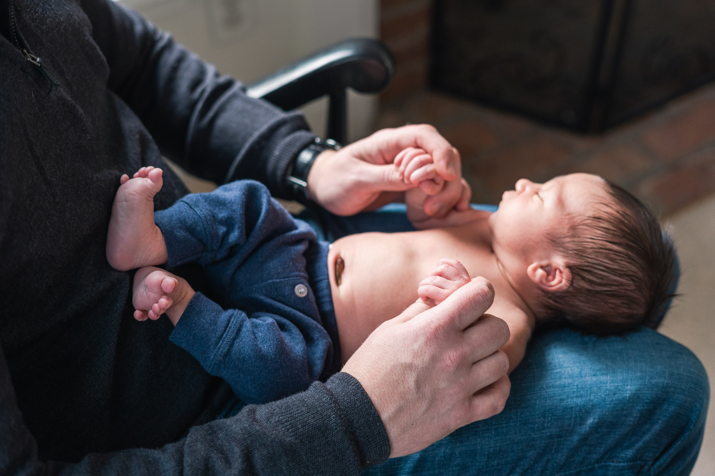 newborn laying in fathers lap