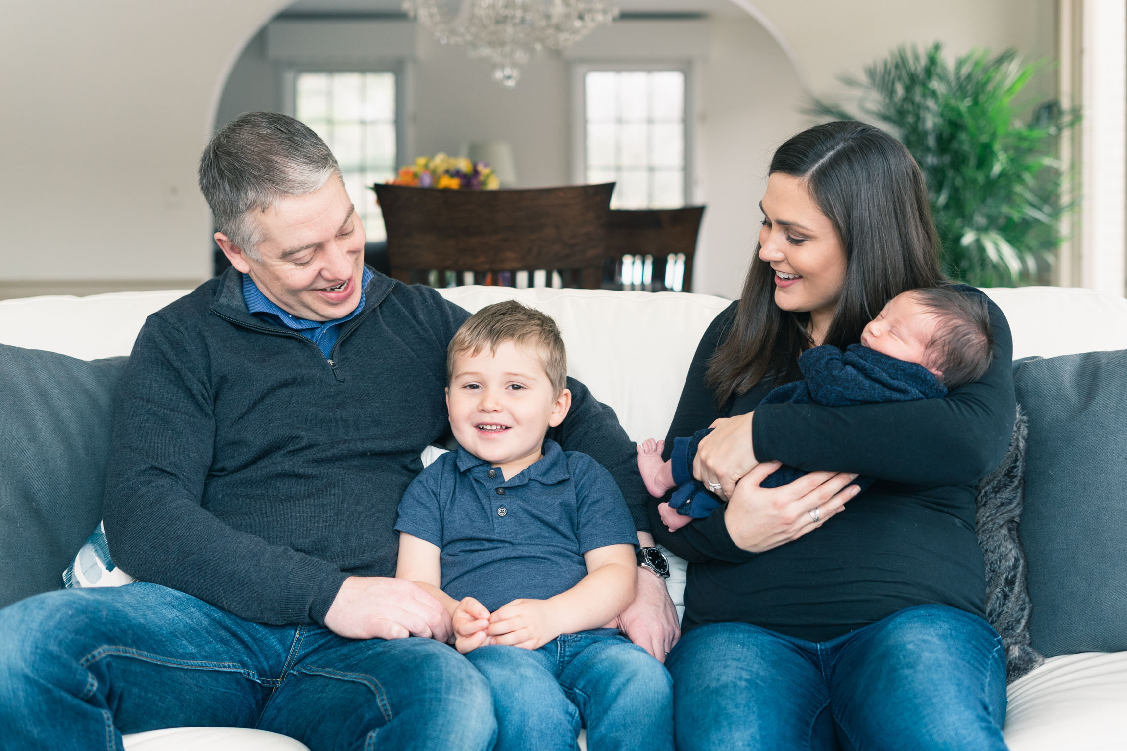 family sitting on couch with newborn