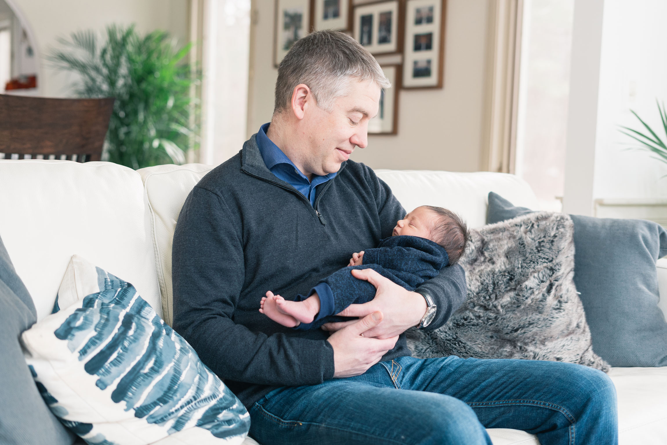 father holding newborn on couch