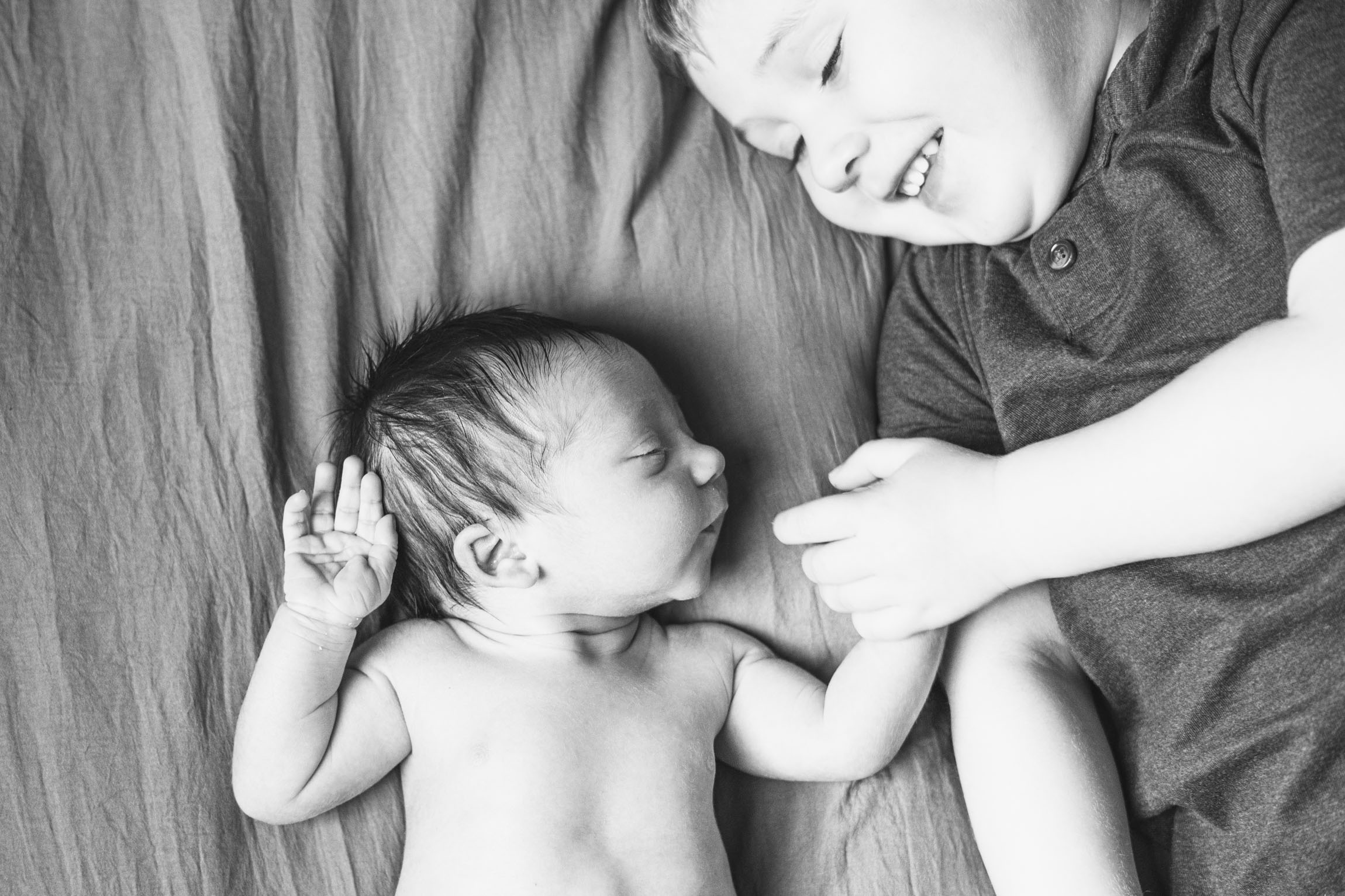 young brother holding newborns hands