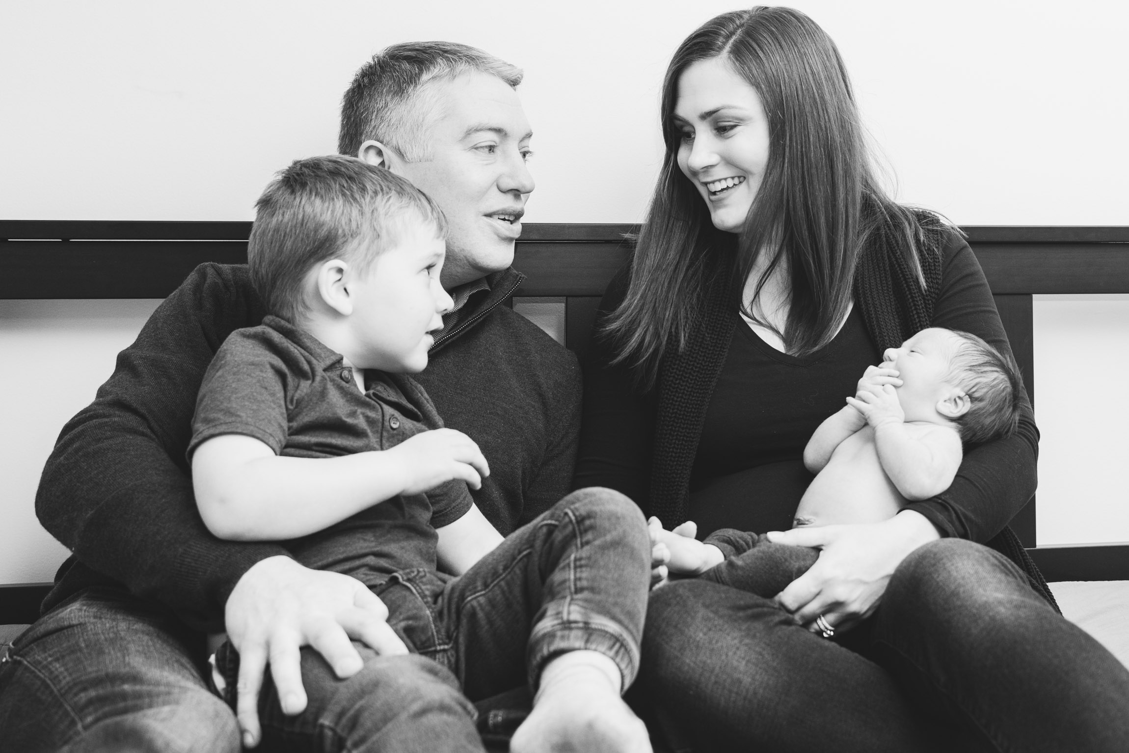 parents cuddling with children on bed