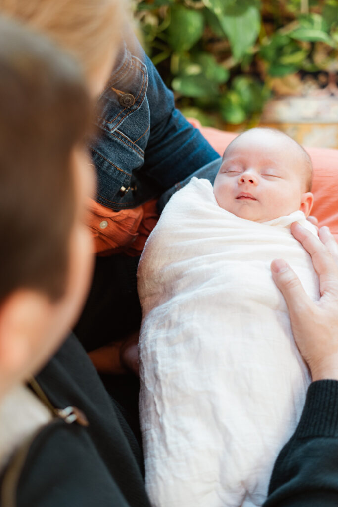 baby wrapped in muslin sleeping on parents lap