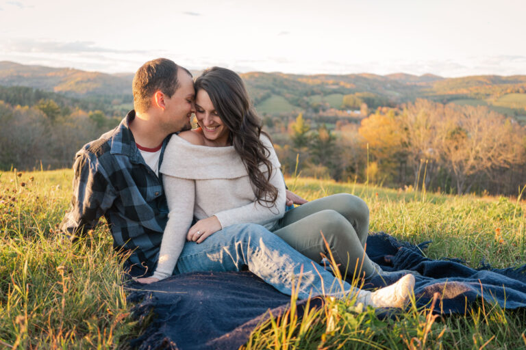 couple snuggling in grass for engagement photos in woodstock, vermont
