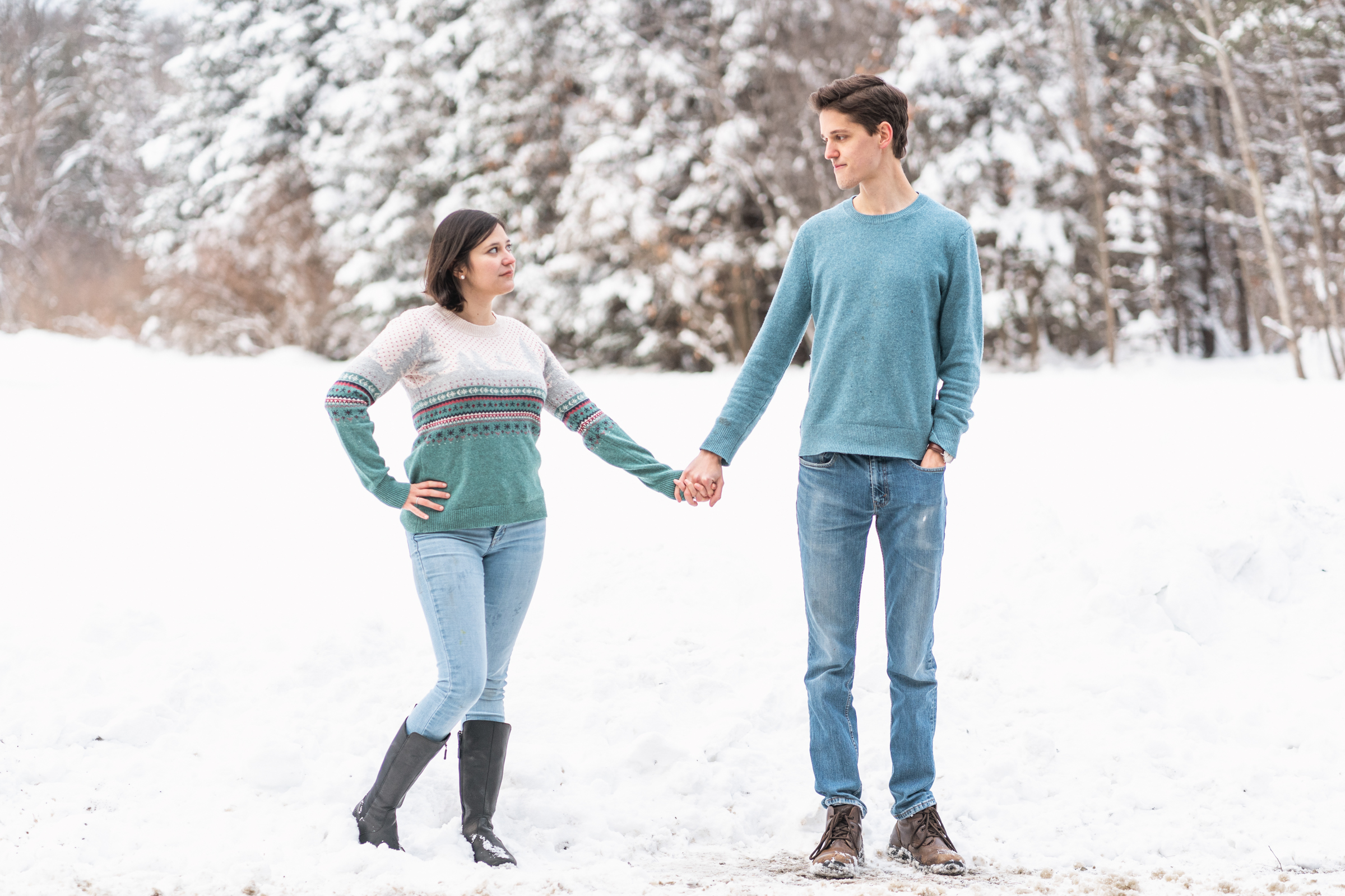 couple holding hands looking at each other with snowy background