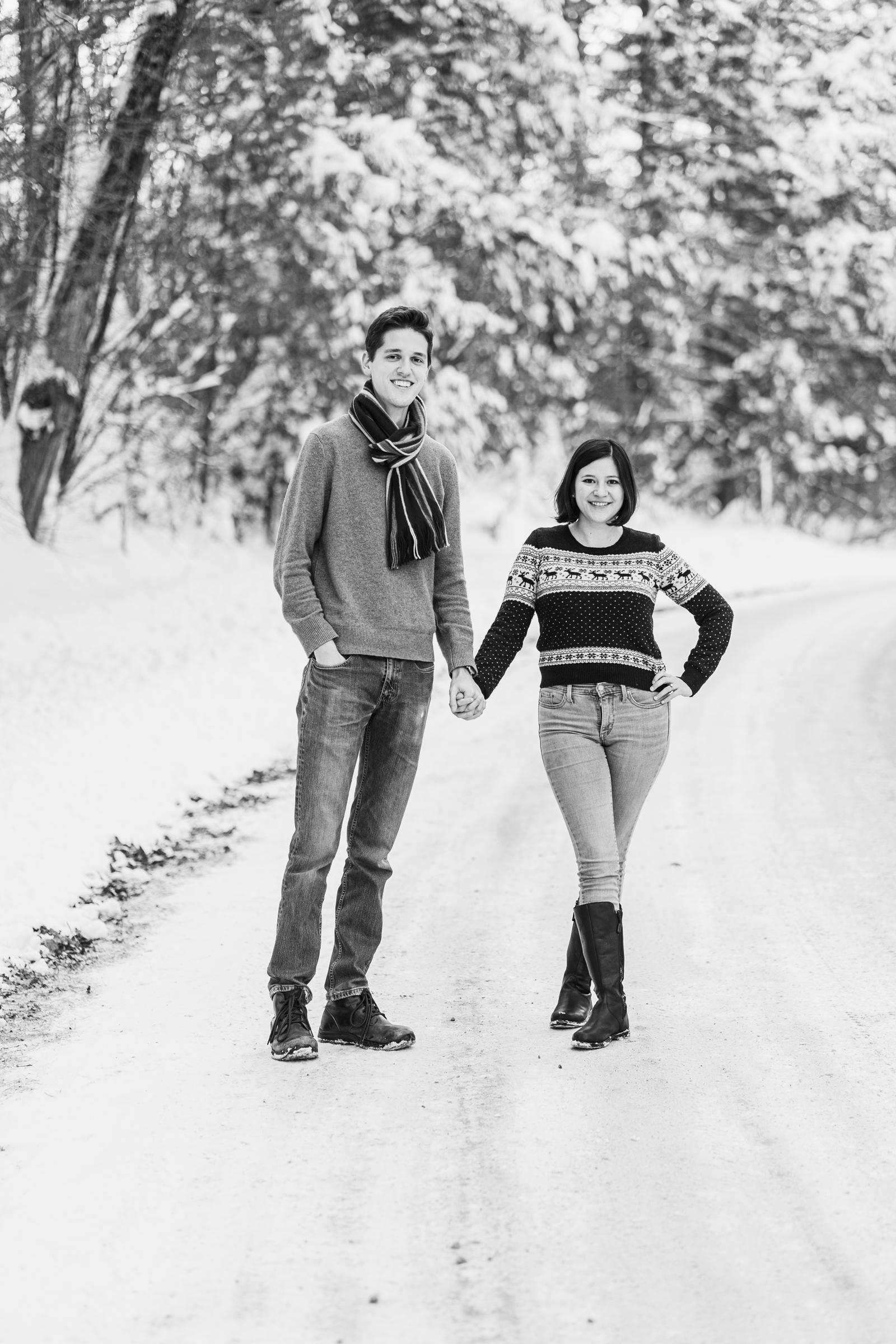 couple holding hands standing on snowy road