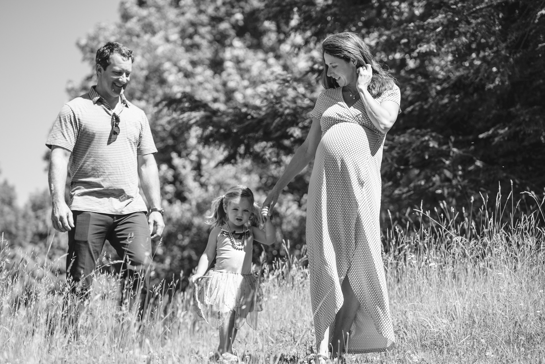 family walking through grass, mom is pregnant
