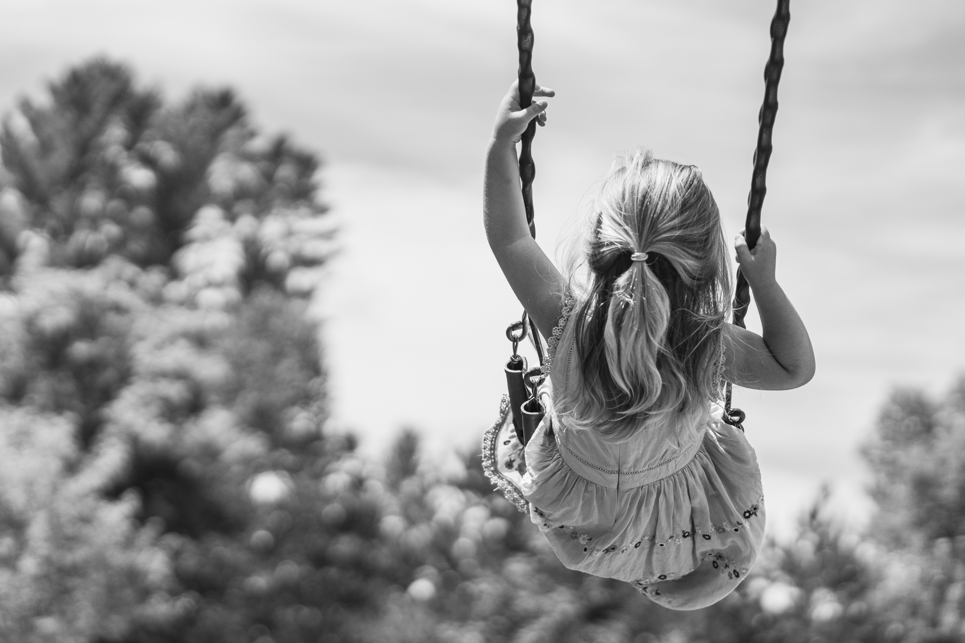 back of young girl swinging