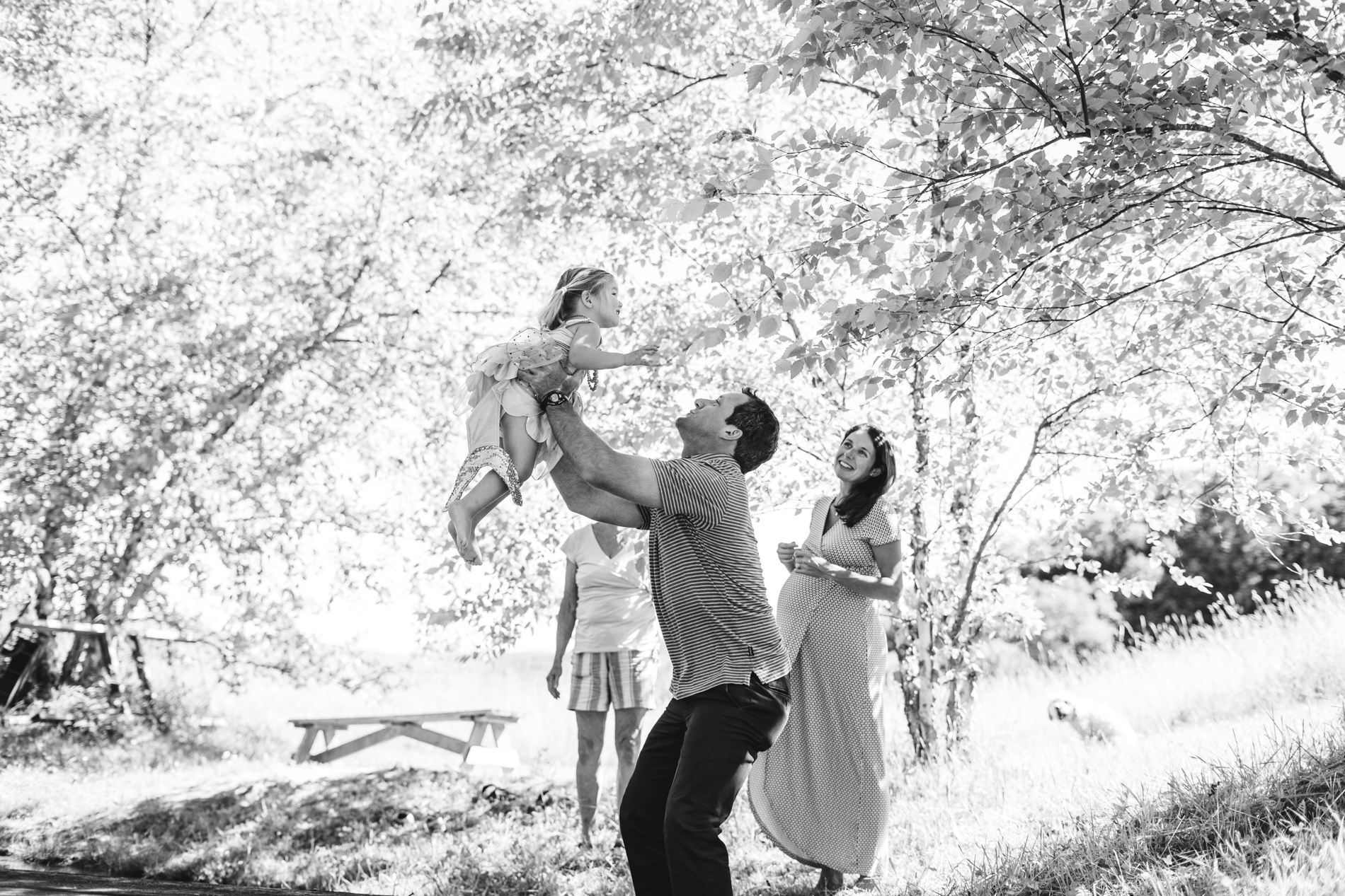 daddy lifting child under trees