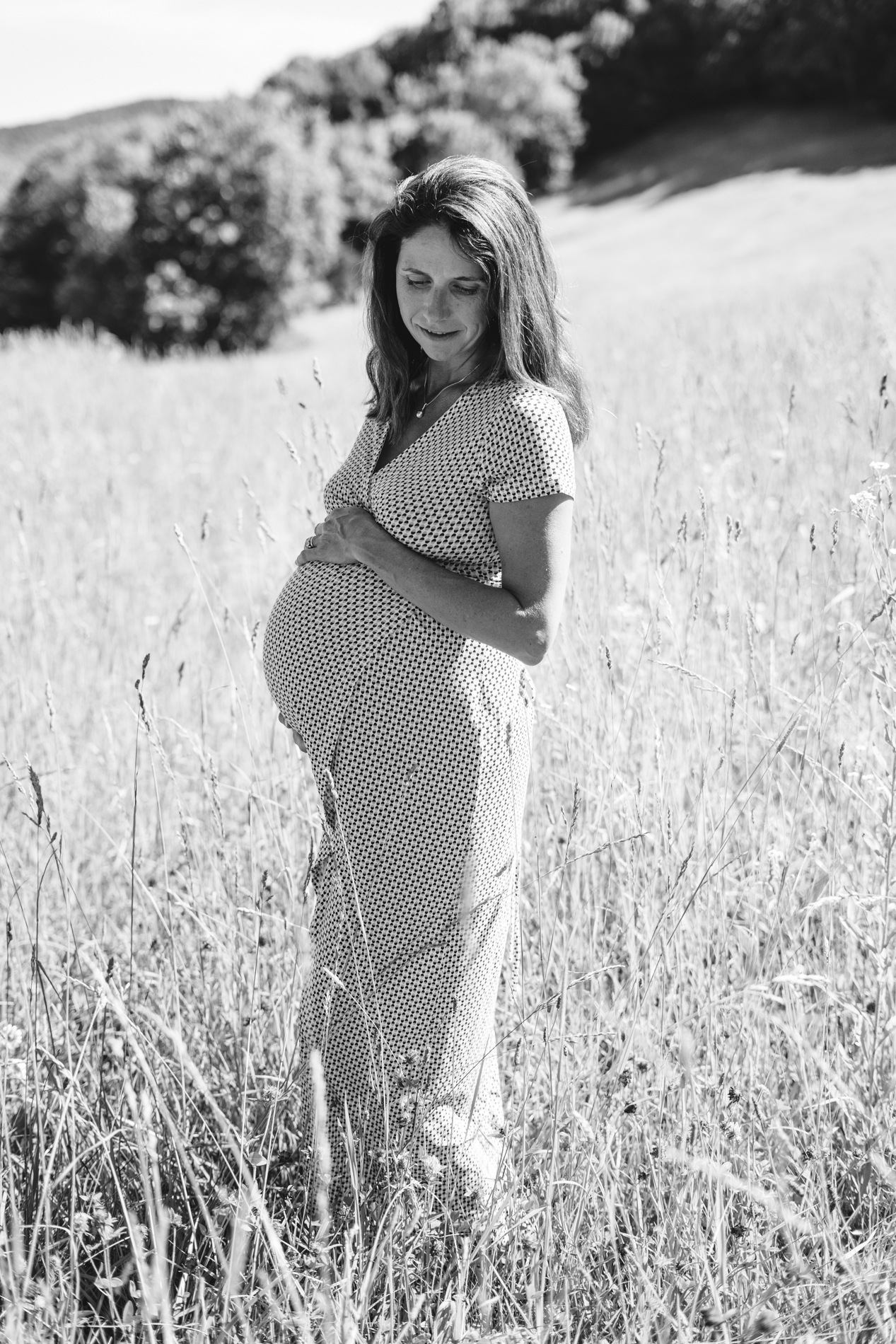 woman looking down posing in full sun for maternity portrait