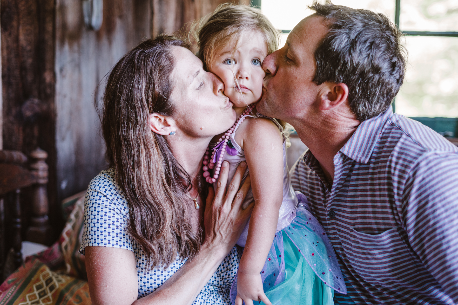 Parents sandwich daughter with kiss