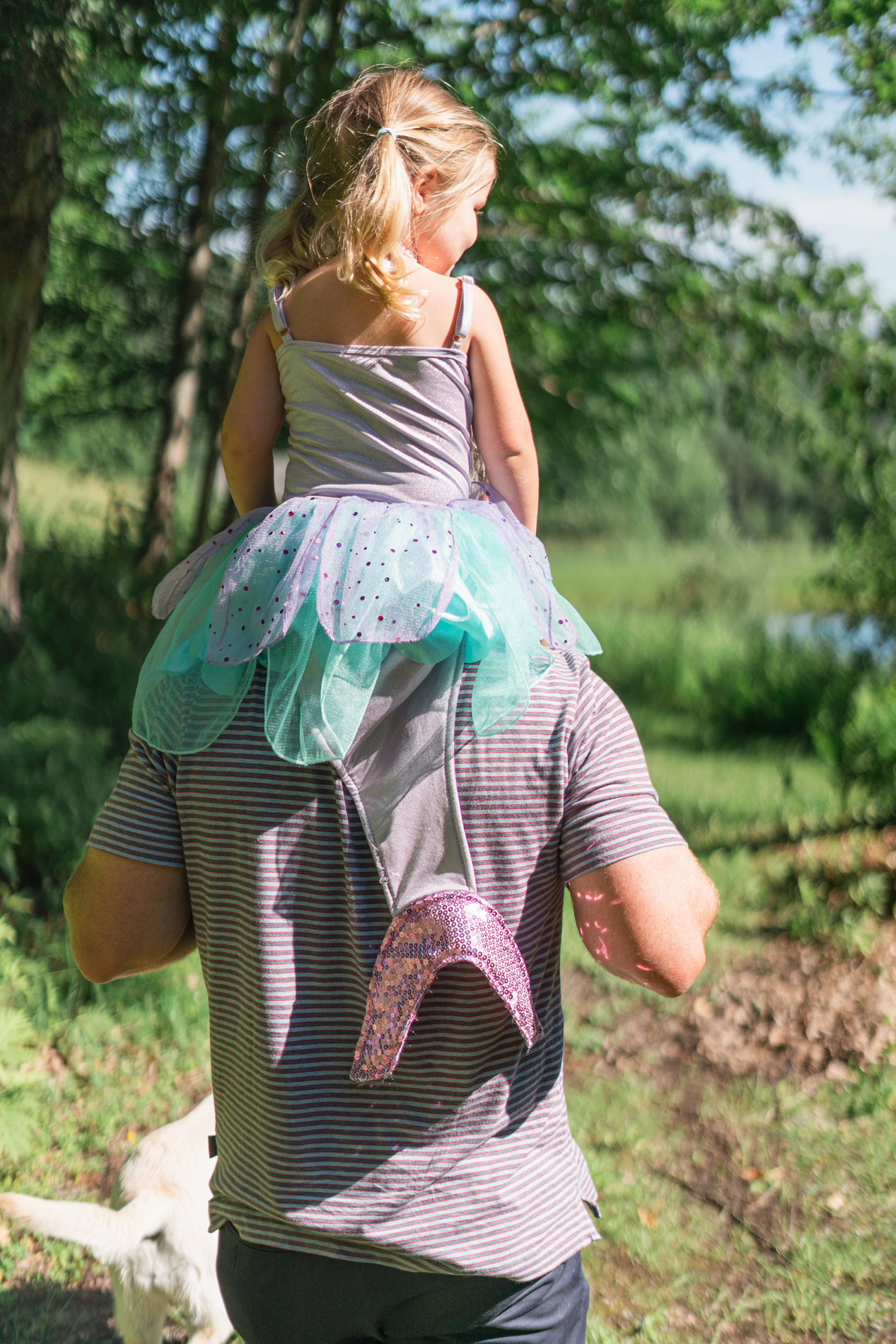 young girl in mermaid costume sitting on daddy's shoulders