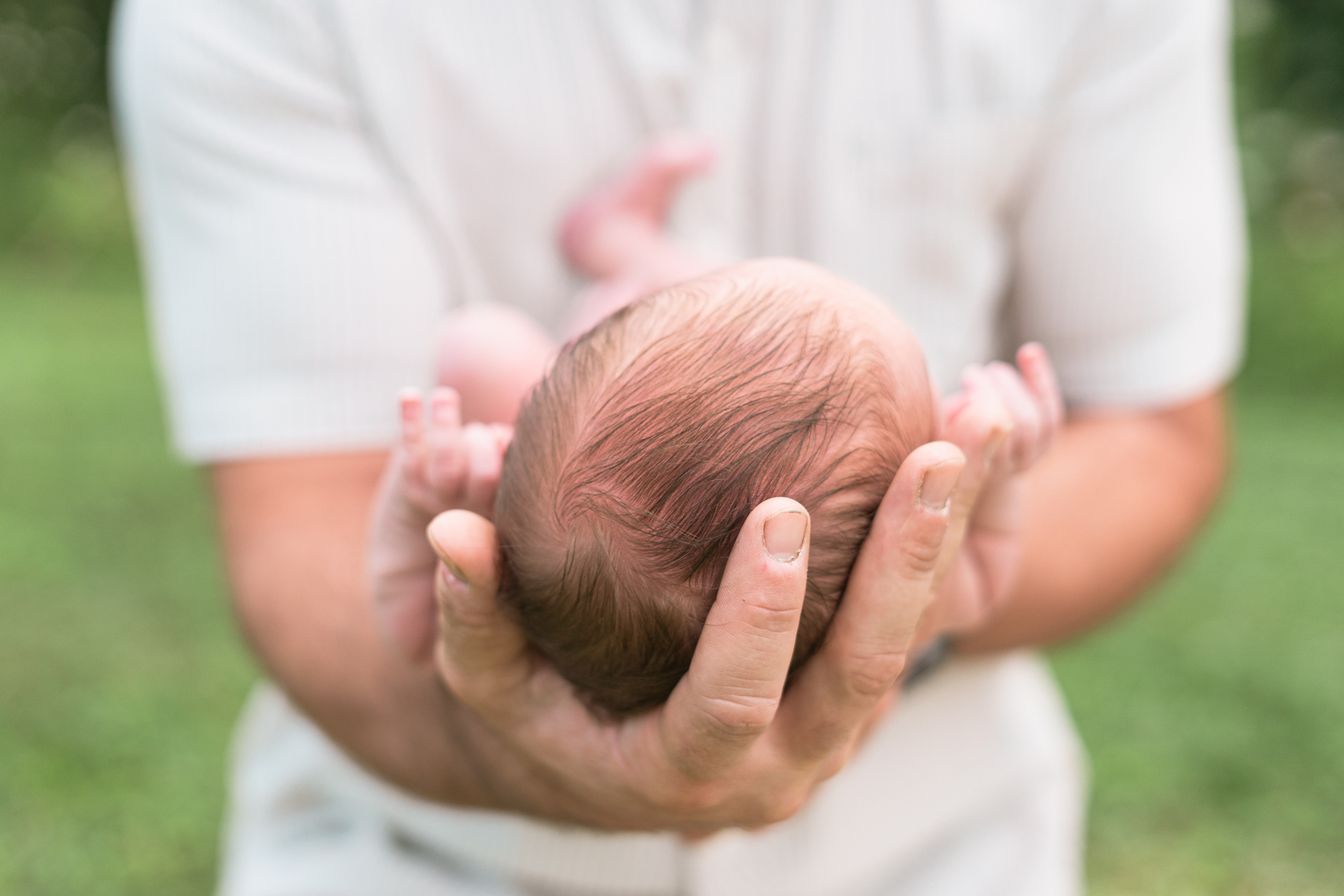 dad cradling tiny newborn head