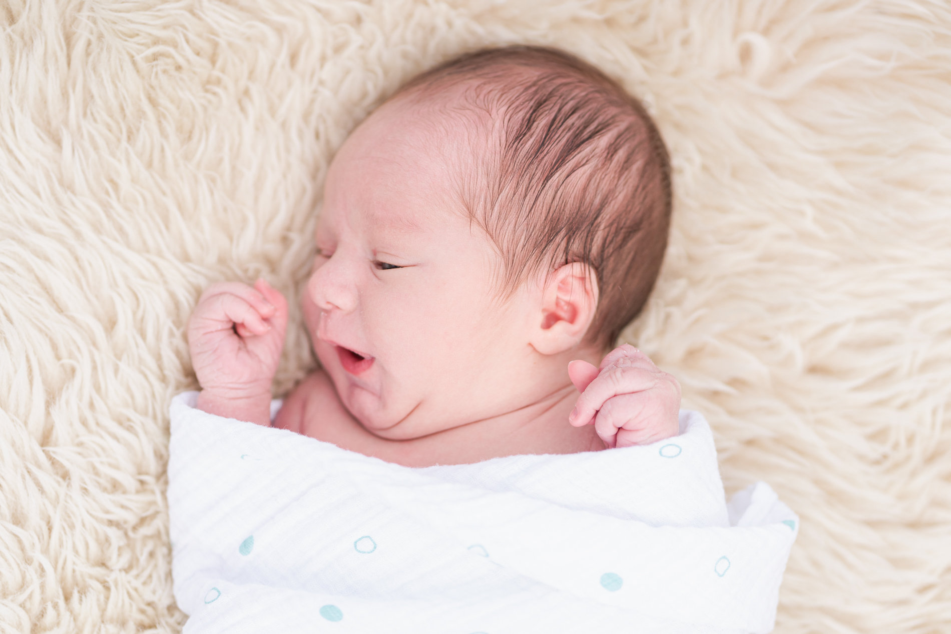 newborn sleeping on furry rug