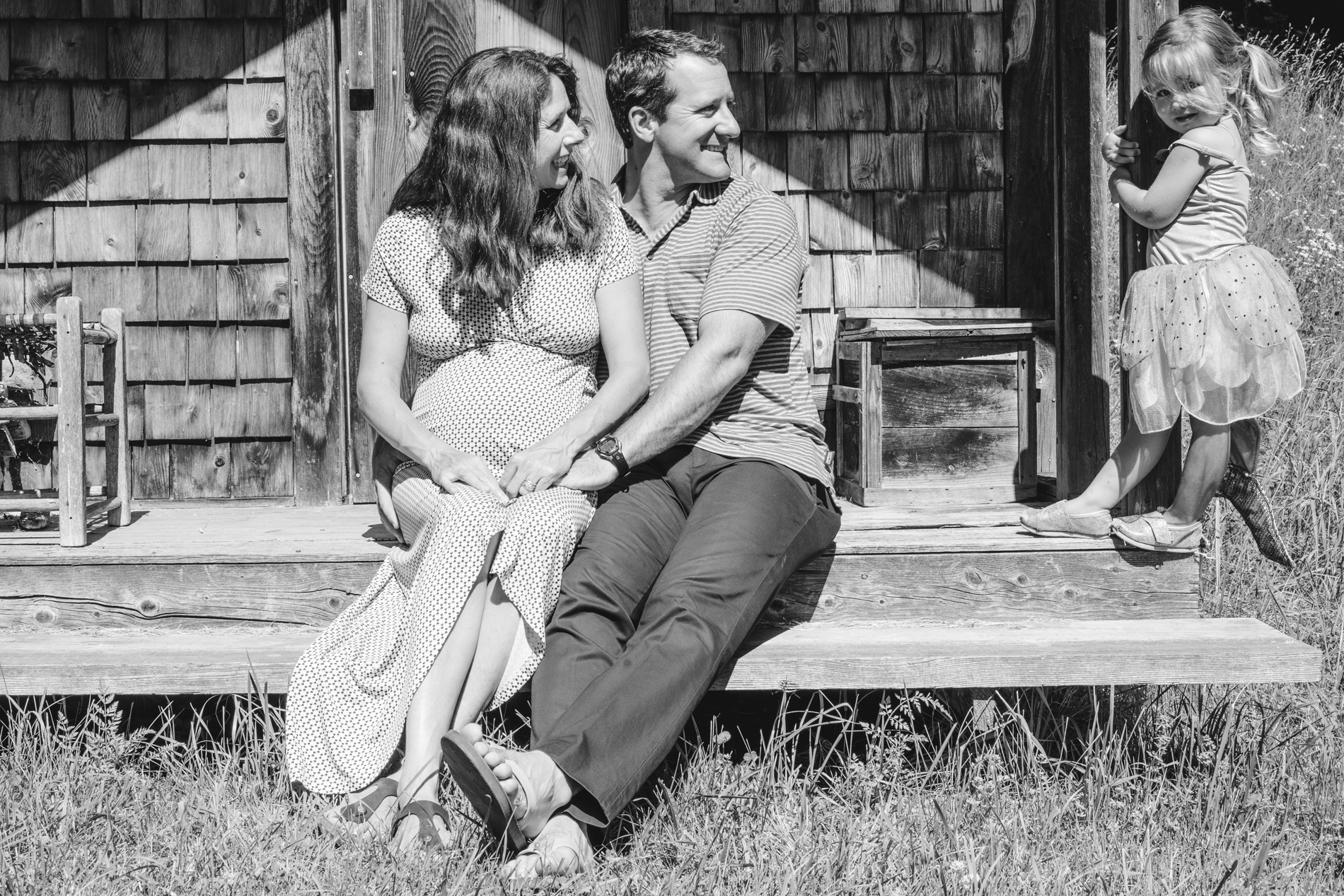Parents sitting on cabin porch looking at daughter looking at camera