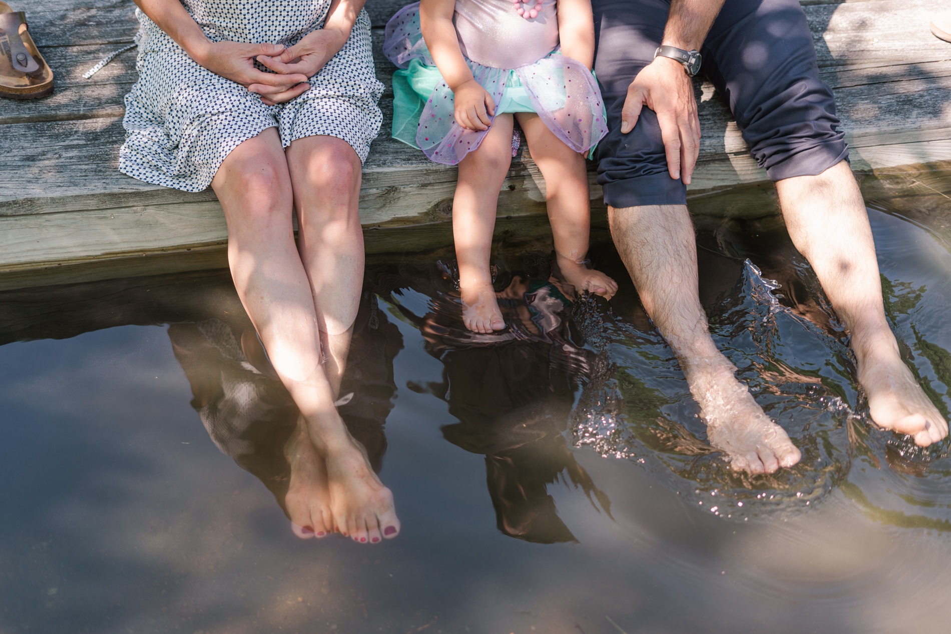 family sitting on doc with legs in water