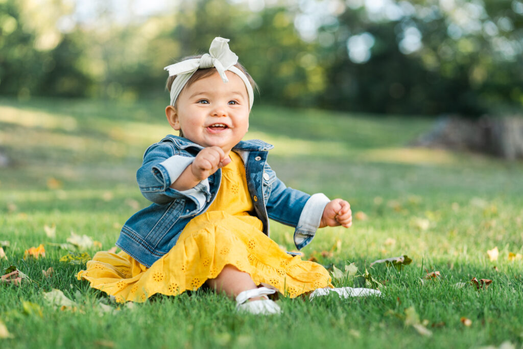 little girl in golden yellow dress sitting in grass at fall upper valley family photo session