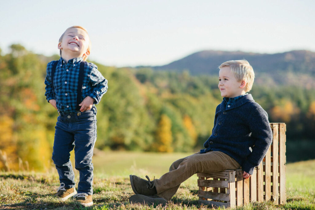 boys sitting on crates and laughing at each other on fall day in new england with views of New Hampshire mountains