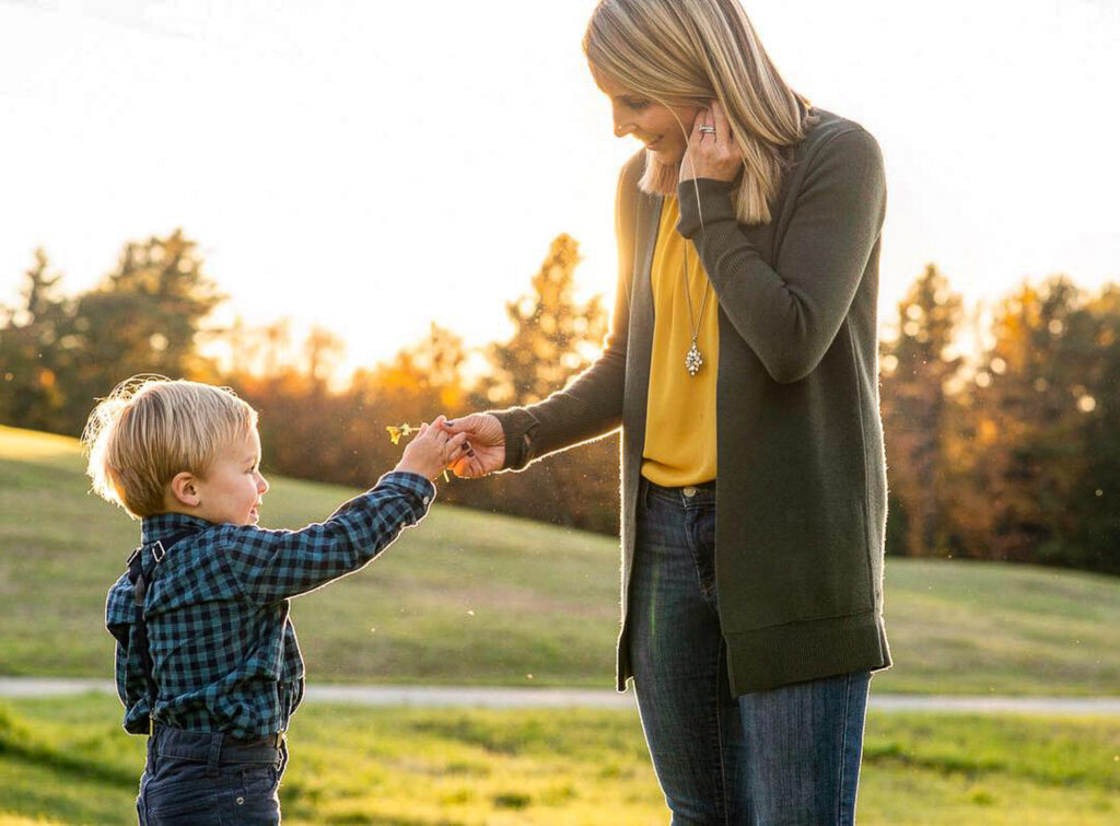 small son handing mother a flower at fall family photo session in the upper valley of NH and VT