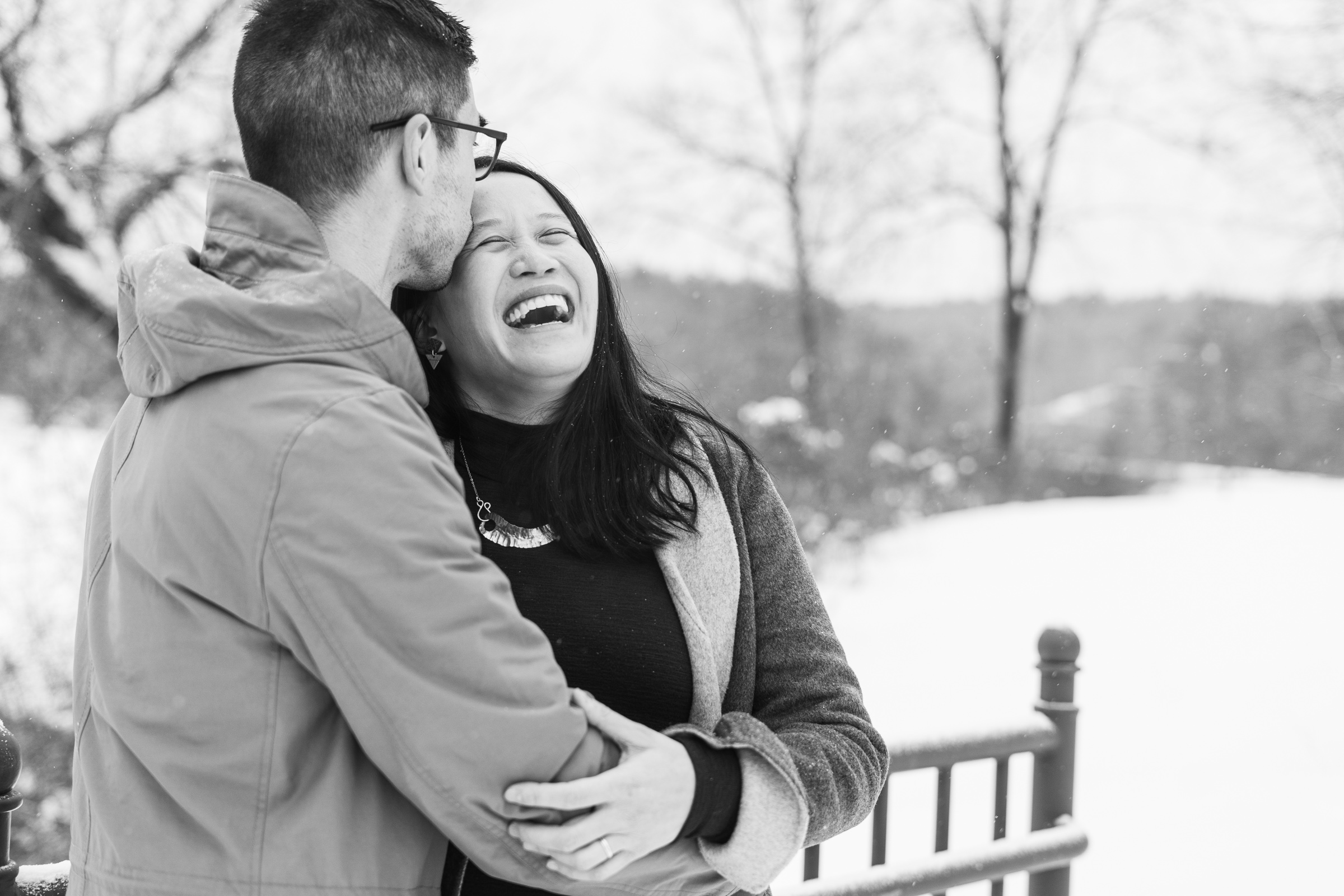 Couple laughing and smiling with snowy scene in background