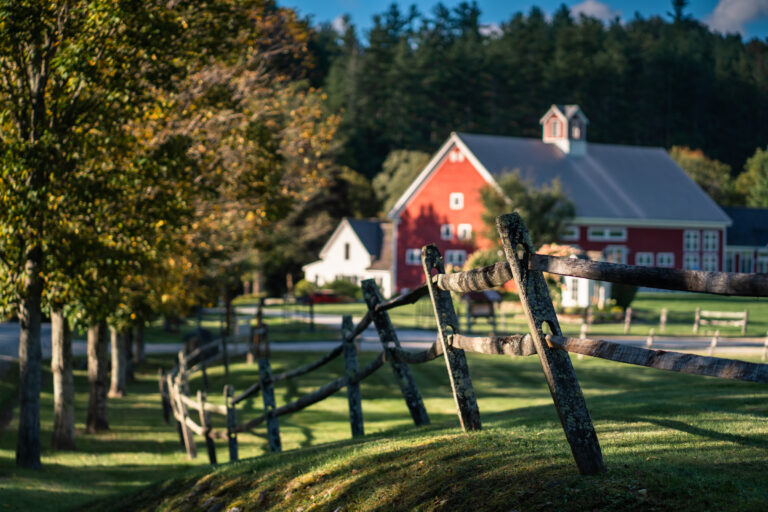 classic image of split rail fence leading to riverside farm
