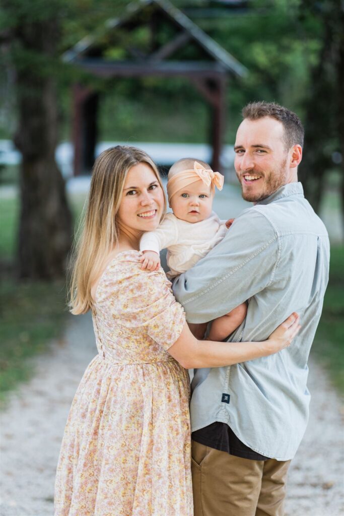 family with baby walking toward covered bridge looking at camera