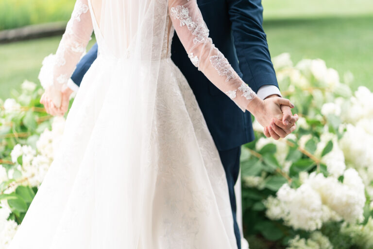photo of bride and groom standing together holding hands, doing airplane, cropped below shoulders