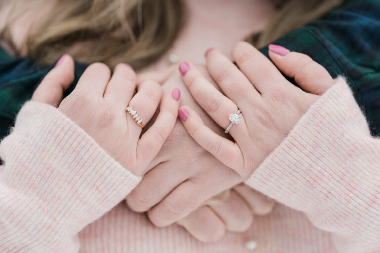 woman's hands crossed over fiance's hands on chest, wearing engagement ring and mother's diamond band