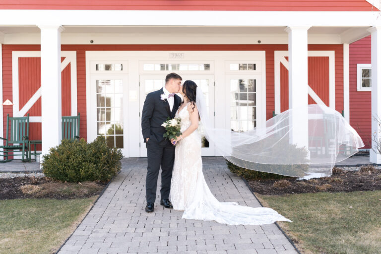 Couple in front of entrance to Inn at Manchester reception venue - veil blowing in air
