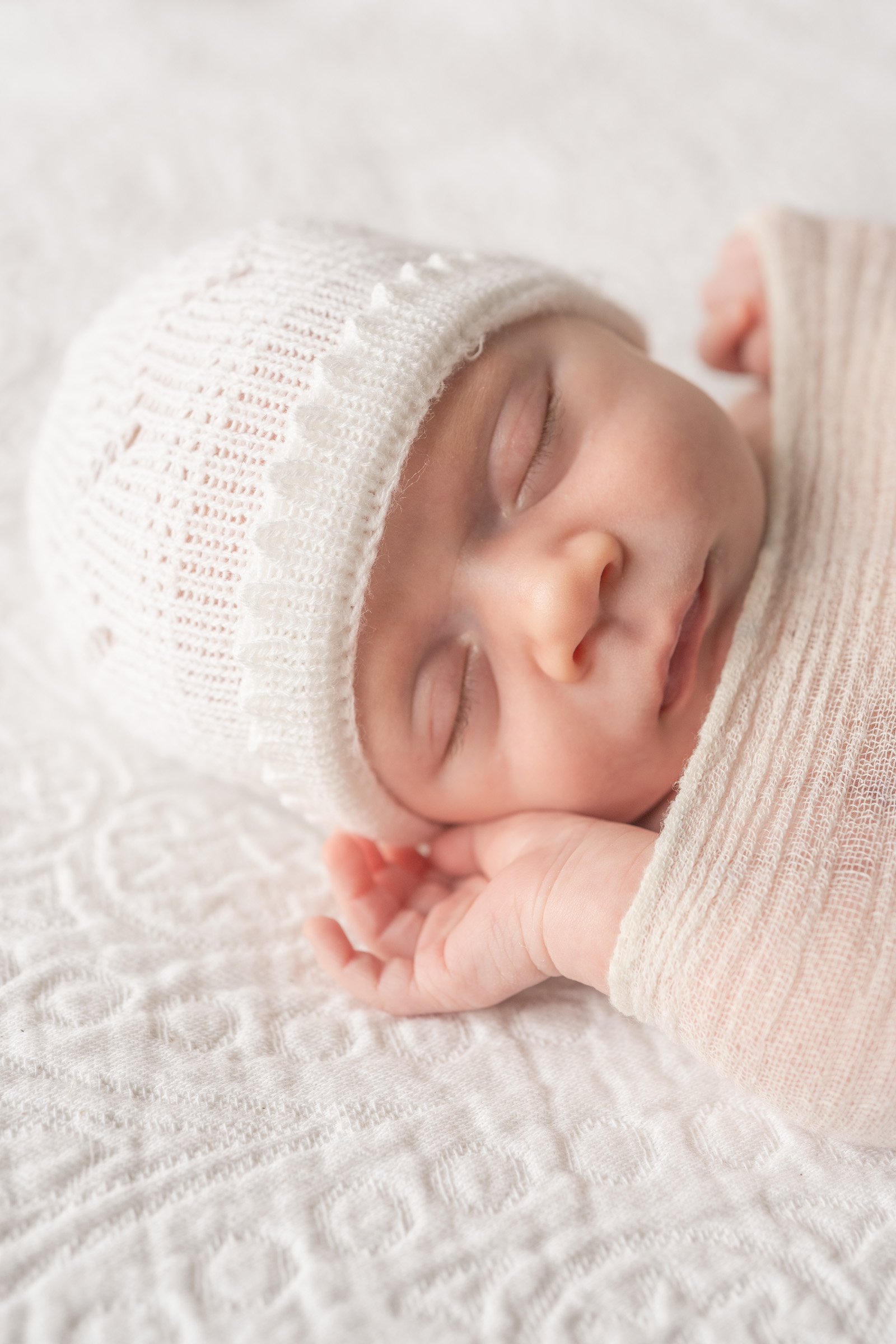 baby sleeping with knit hat, little hands tucked by face