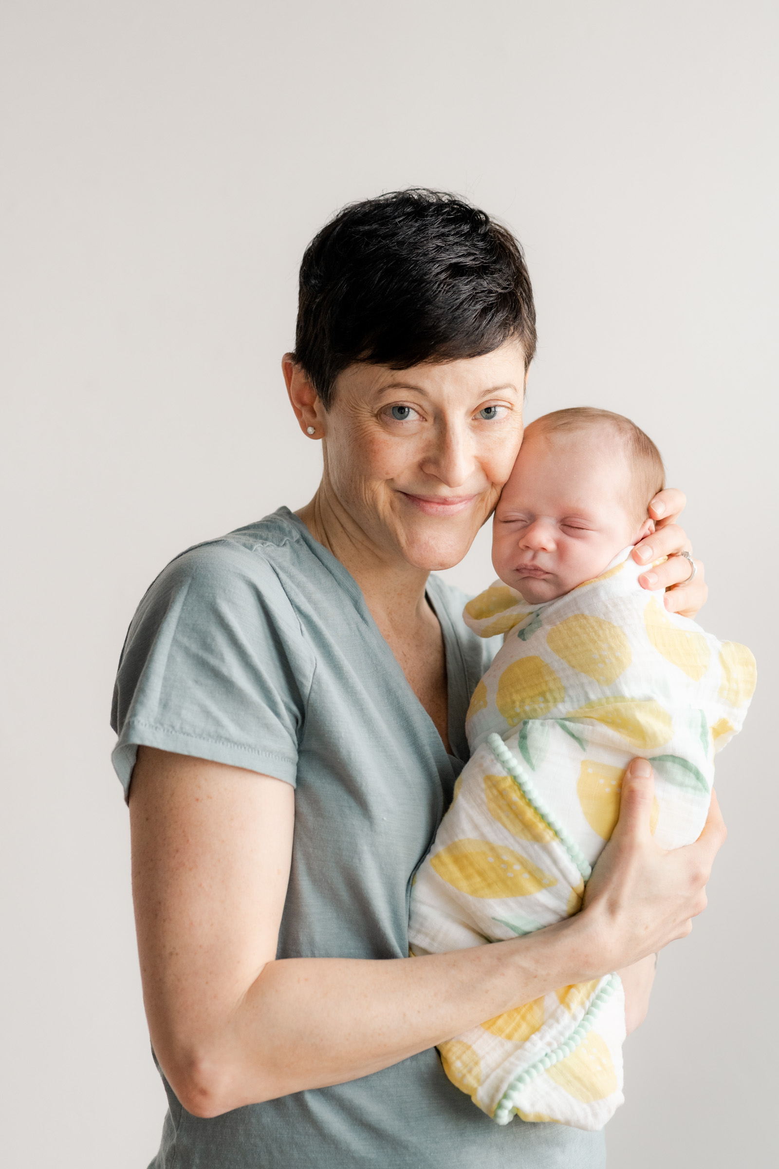 mom holding baby near her cheek with baby in lemon swadle