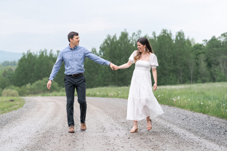 couple hold hands and playfully walk down road