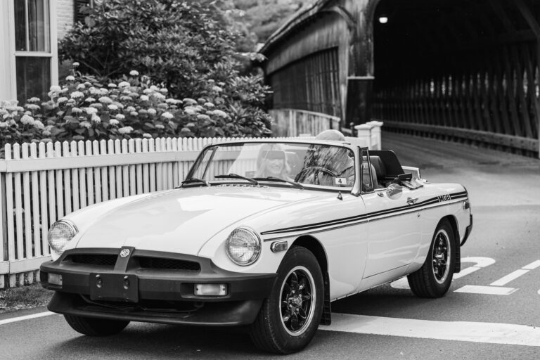 couple driving away from bridge in mg convertible