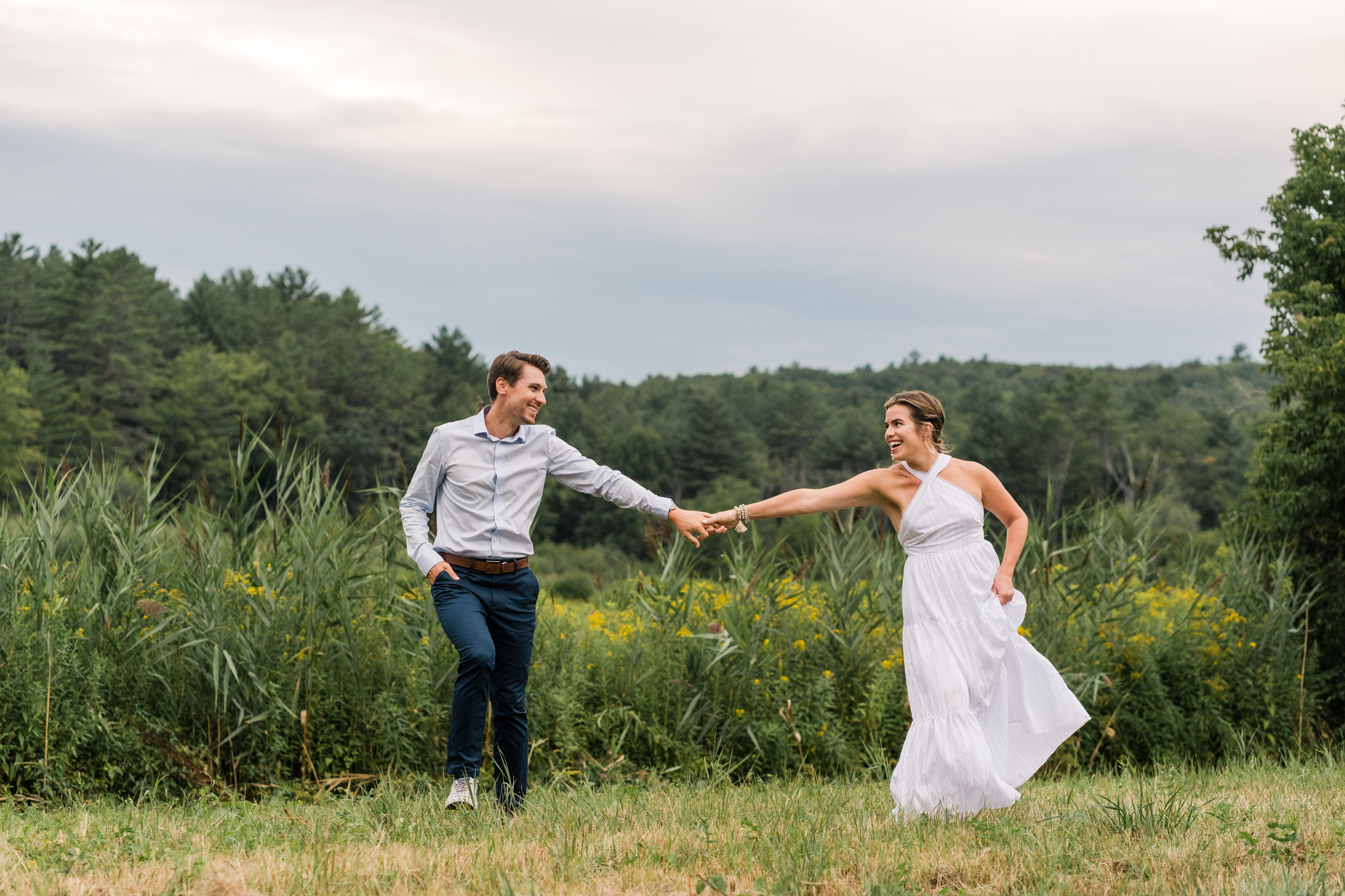 couple meander playfully in grass at quechee vermont enegagement session