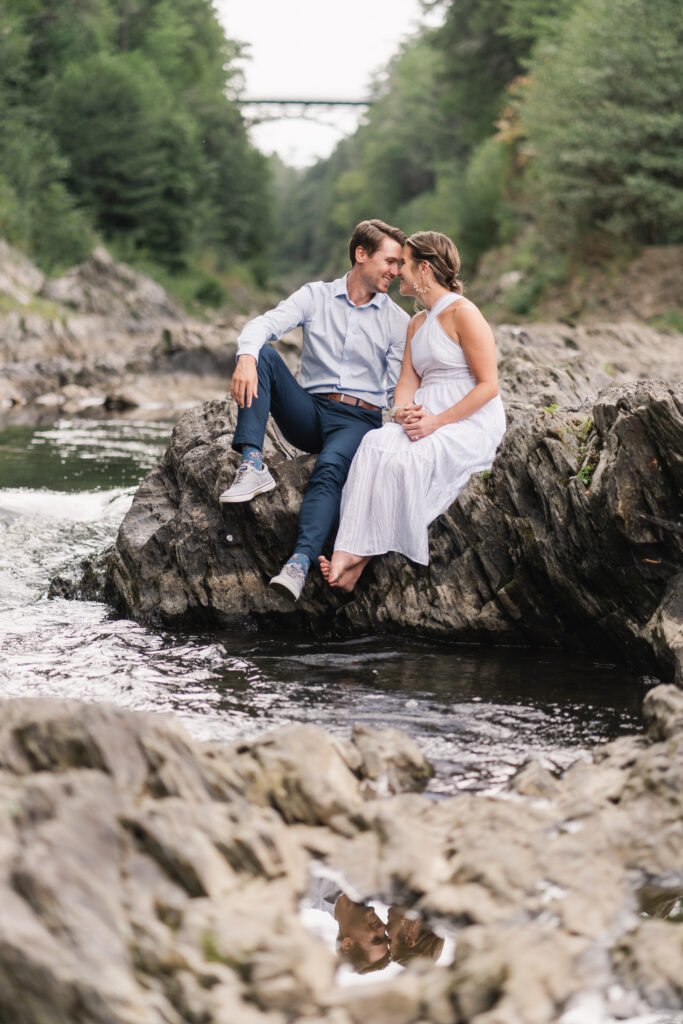 couple snuggle, forehad to forehead on rock at quechee gorge engagement session