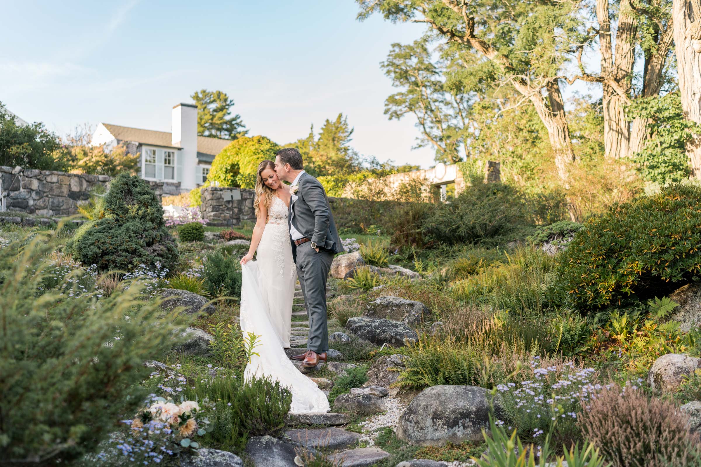 groom kisses bride in rock garden at The Fells