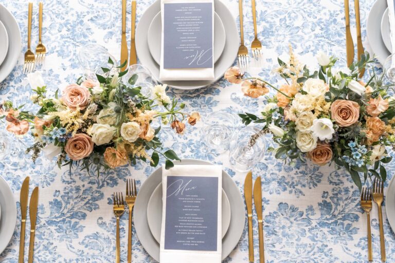 top-down view of beautiful blue table lines, china, and flatware, as well as floral centerpieces at wedding reception