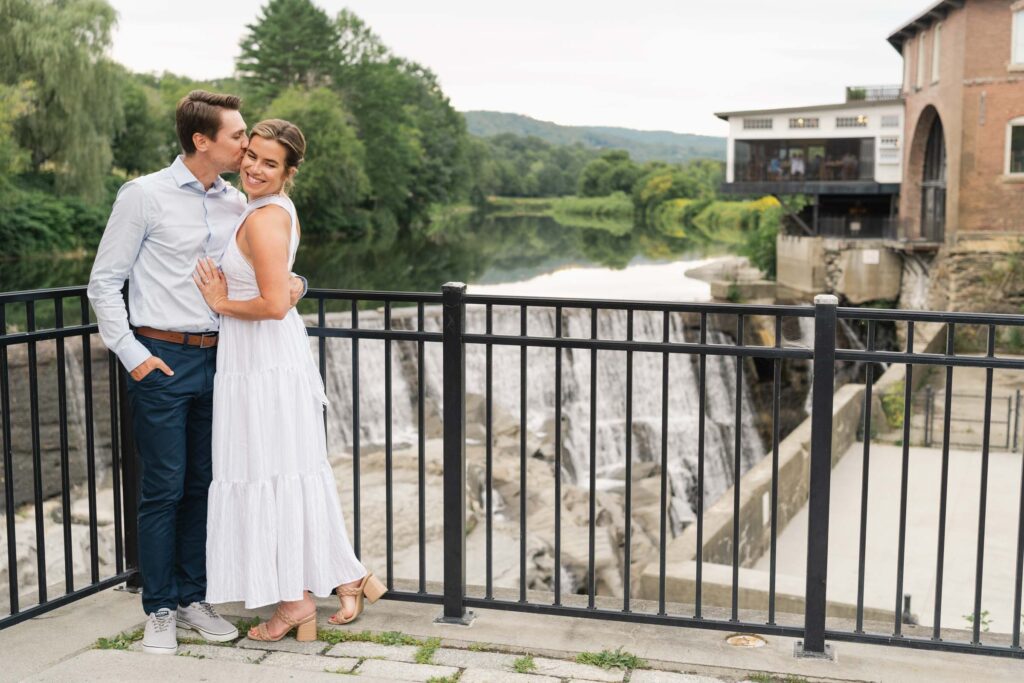 Couple standing near Simon Pearce and river in background, Quechee, Vermont