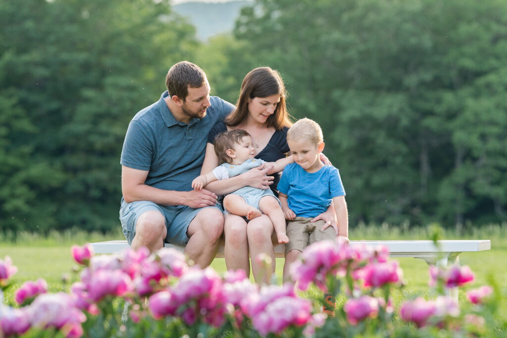 family sitting on bench with flowers in the foreground