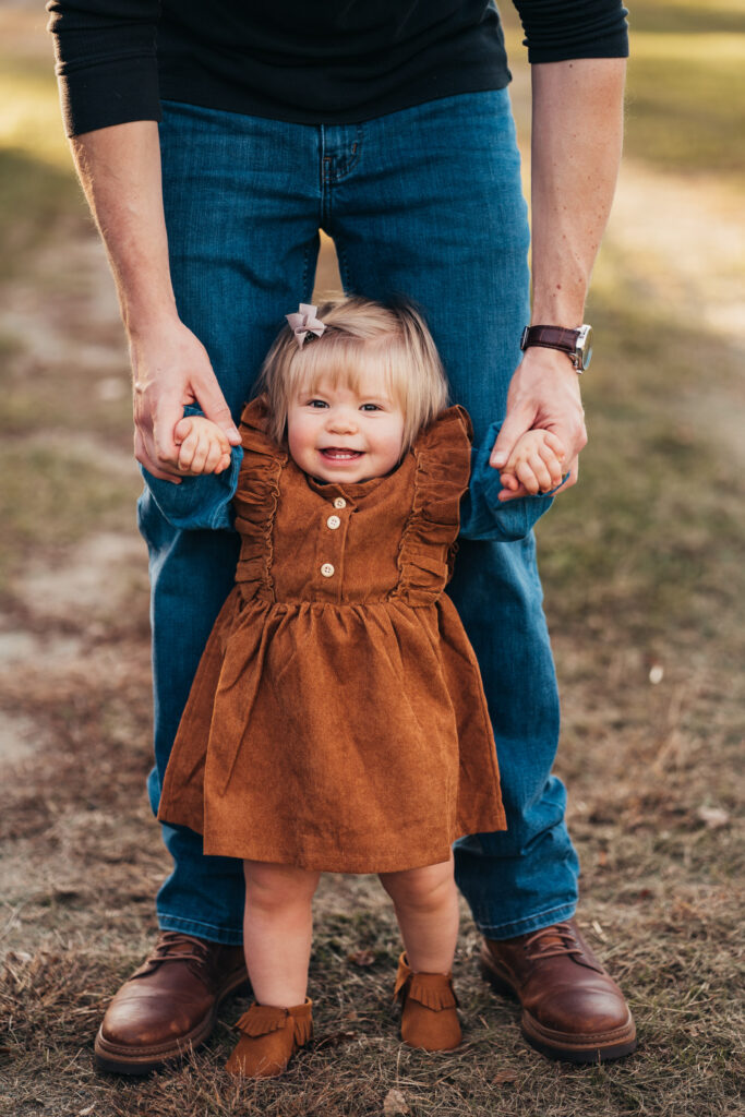 father holding hands helping daughter walk during fall family photo session in the upper valley of NH and VT
