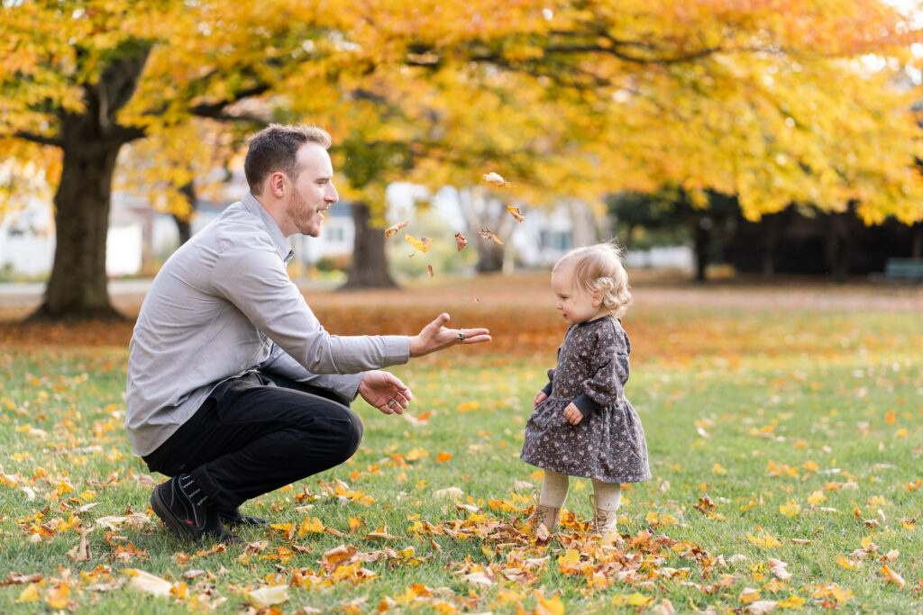 father interacting with daughter with gold tree behind them at woodstock vermont family photo session