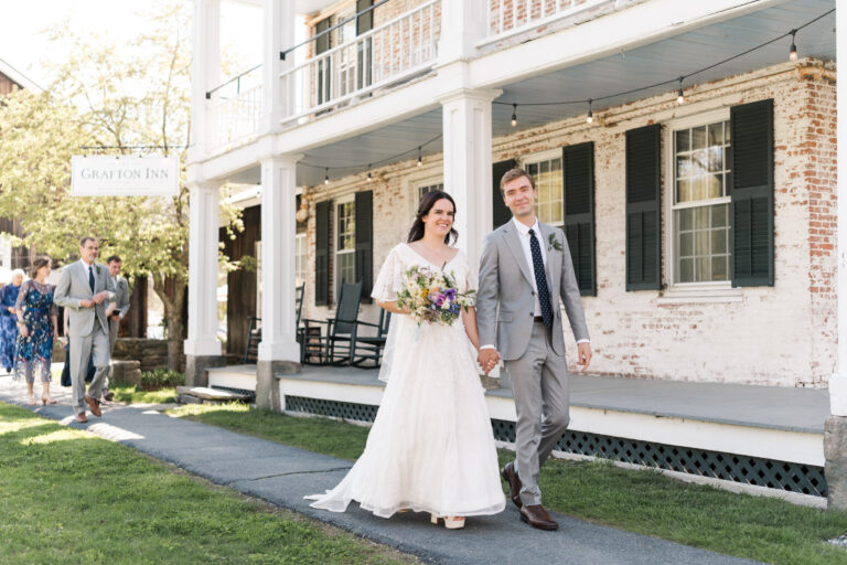 Bride and Groom walk along Grafton Inn on spring wedding day in vermont