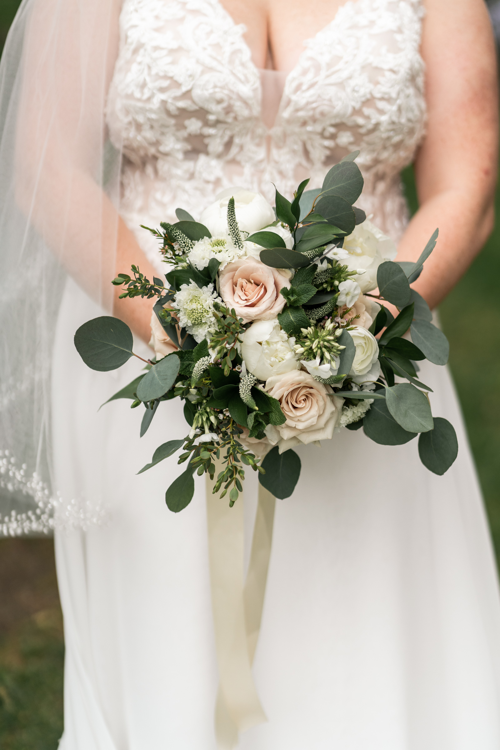 bride holding pastel florals with veil covering shoulders