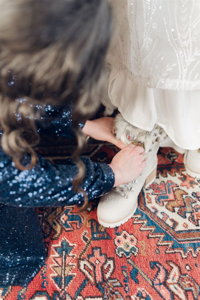 bridesmaid tying winter boots at mountain top inn, chittenden, vt